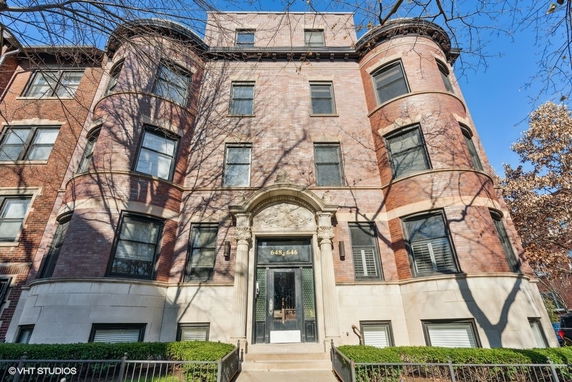 Front view of a multi-story brick building with arched entrance.