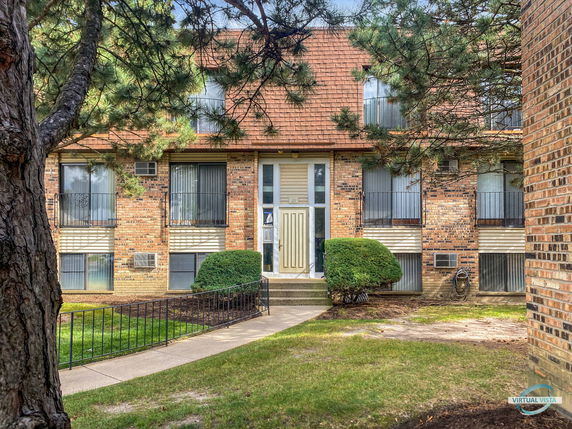 Front view of a two-story building with brick exterior and balconies.