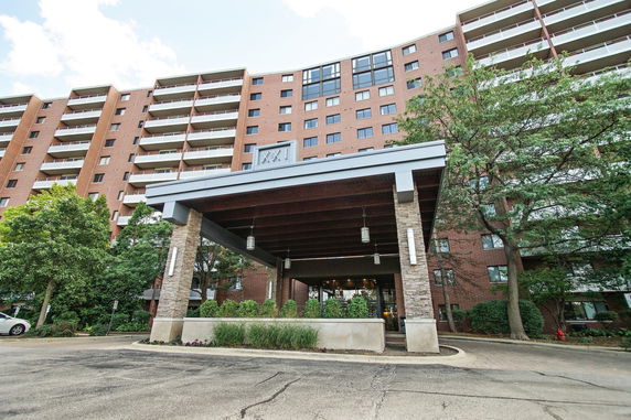 Front view of a multi-story apartment building with a covered entrance.
