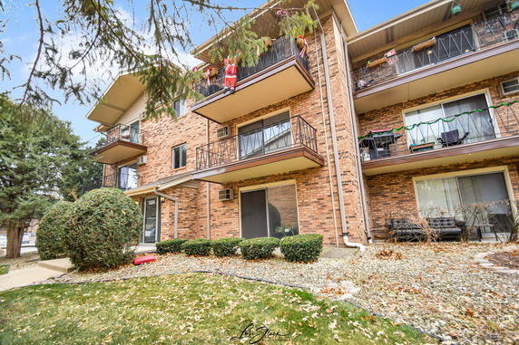 Front view of a multi-story brick apartment building with balconies.