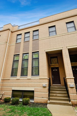 Front view of a multi-story residential building with brick exterior and stair access.