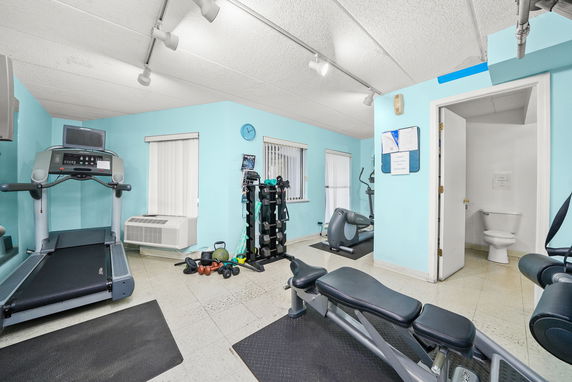 Indoor gym area with exercise equipment and weights.