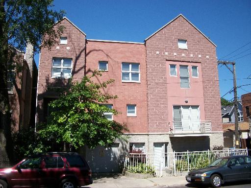 Front view of a multi-story residential building with a brick facade and double pitched roof sections.