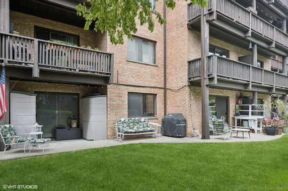 Front view of a multi-story building with balconies and outdoor seating area.