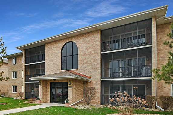 Front view of a multi-story brick building with balconies and arched windows.