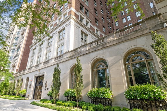 Front view of a multi-story building with arched windows and decorative plants.