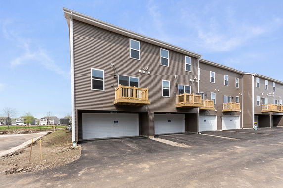Front view of a row of multi-story houses with balconies and garages.