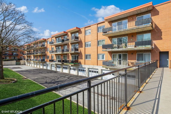Front view of a multi-story apartment building with balconies and garage parking.