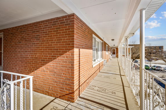 Exterior view of a brick building with a long corridor and metal railing.