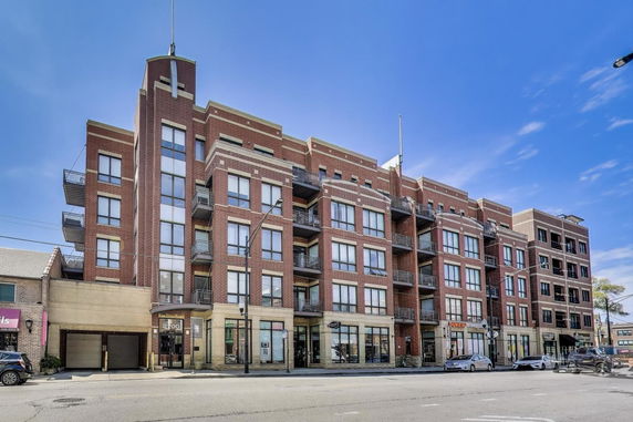 Front view of a multi-story building with brick facade and balconies.