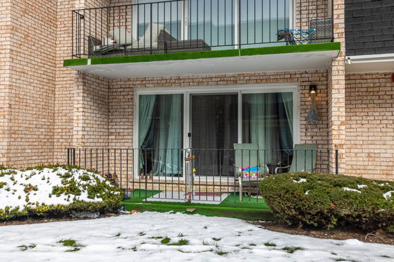 Front view of a building with two balconies and sliding glass doors.