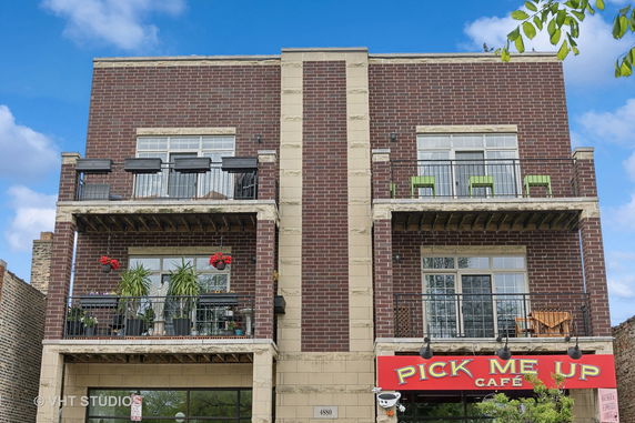 Front view of a brick building with balconies and a café on the ground level.