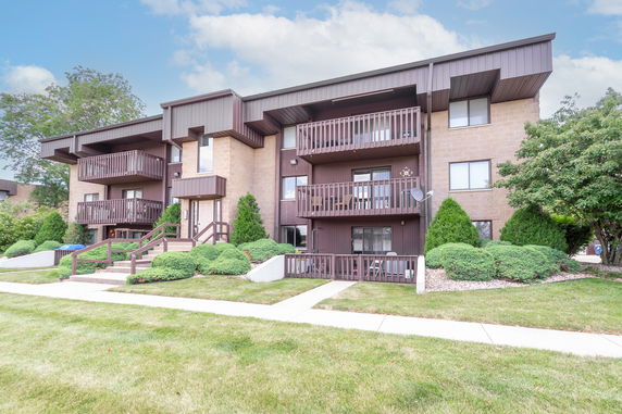 Front view of a two-story building with balconies and a landscaped entrance.