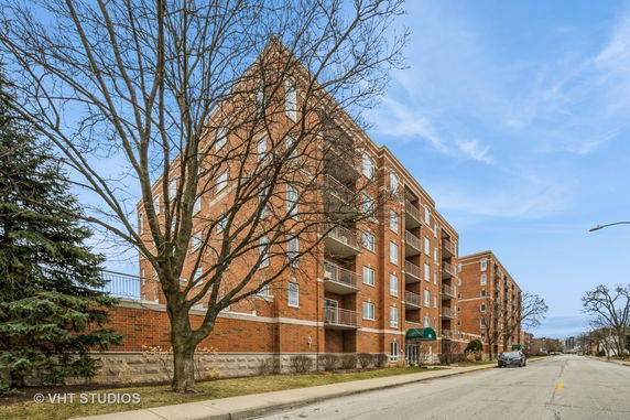 Front view of a multi-story brick apartment building with balconies.