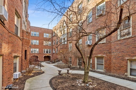 View of a brick apartment building exterior with multiple windows and a central courtyard.