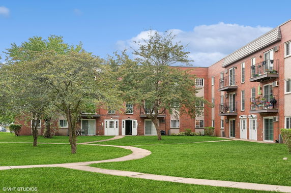 Front view of a multi-story apartment building with balconies and large windows.