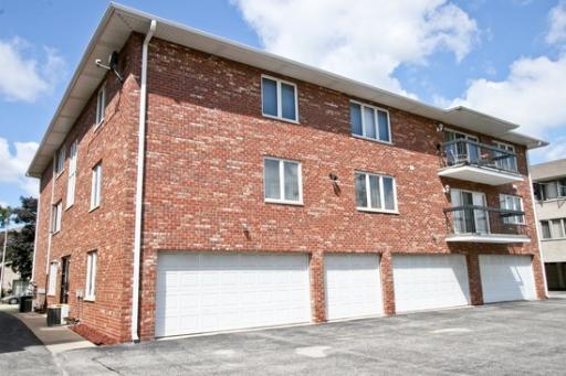 View of a three-story brick building with multiple garages on the ground floor.