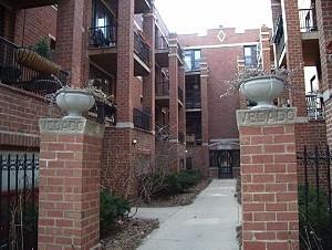 Front view of a multi-story apartment building with brick exterior and entrance pathway.