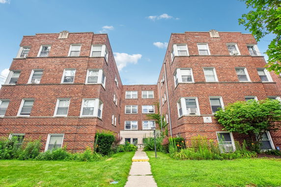 Front view of a multi-story brick apartment building with numerous windows.