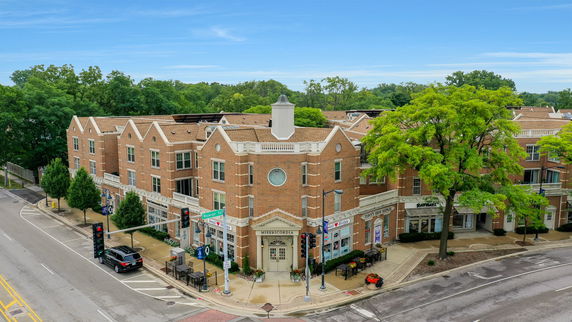 Front view of a three-story brick building with retail shops on the ground floor.