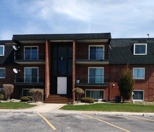 Front view of a three-story apartment building with balconies and a central entrance.