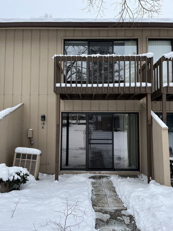 Front view of a two-story building with balconies and a pathway covered in snow.