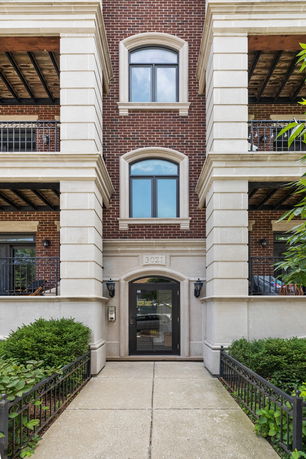Front view of a multi-story building with brick facade and balconies.