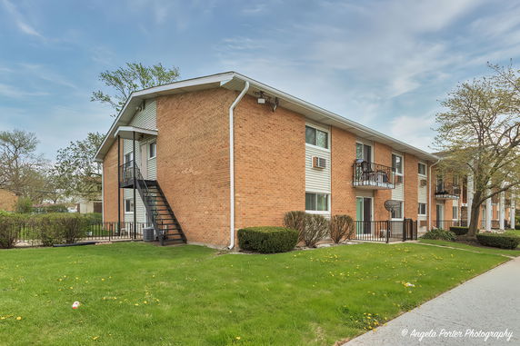 Front view of a two-story apartment building with brick exterior and balconies.