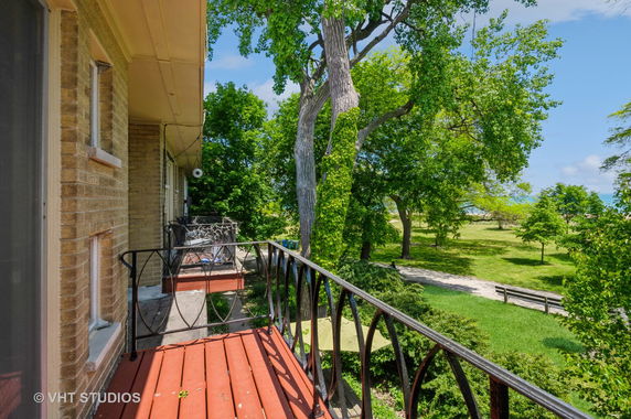 Balcony view overlooking grassy area with trees.