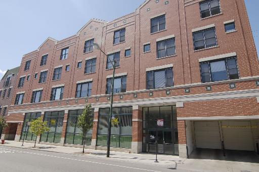 Front view of a multi-story brick building with large windows and an entrance.