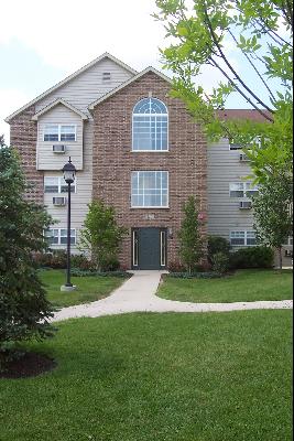 Front view of a multi-story residential building with a brick facade and large arched windows.