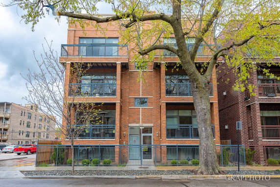 Front view of a multi-story brick building with balconies and large windows.