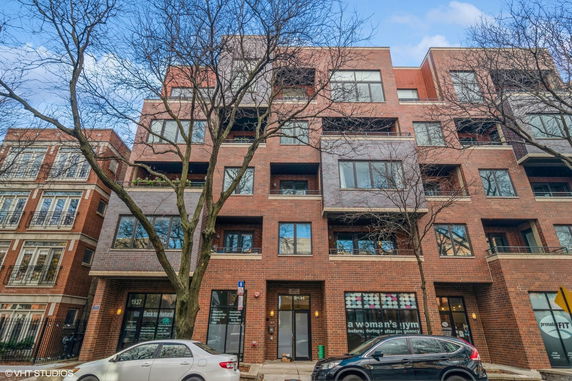 Front view of a multi-story brick apartment building with large windows.