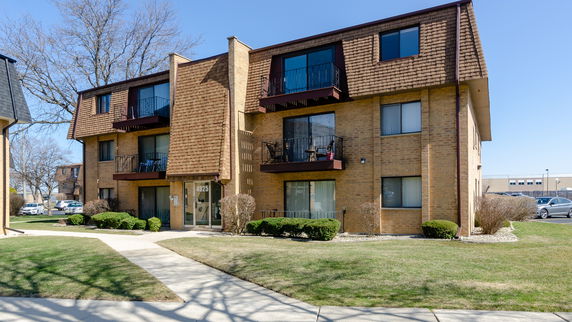 Front view of a three-story apartment building with balconies and a brick facade.