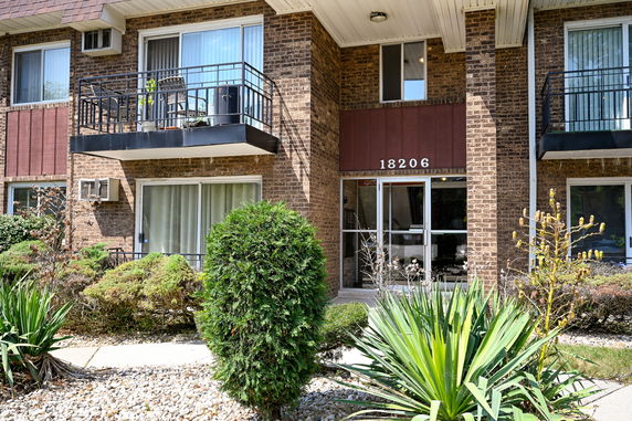 Front view of a brick building with balconies and a central entrance.