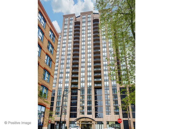 Front view of a multi-story residential building with balconies and glass windows.