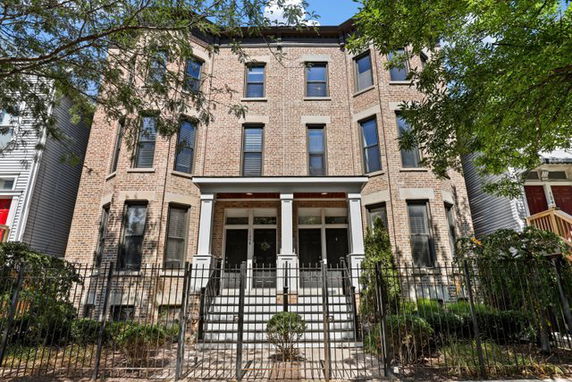 Front view of a multi-story brick building with a gated entrance.