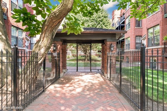 Entrance gate and pathway leading to a brick building with windows.
