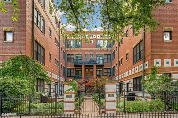 Front view of a multi-story brick apartment building with balconies.
