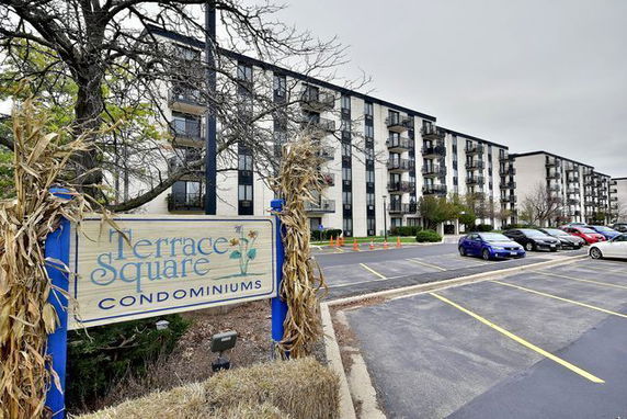 Front view of a multi-story condominium building with a parking lot.