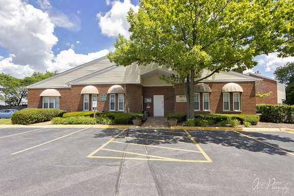 Front view of a single-story brick building with arched window awnings and a main entrance.