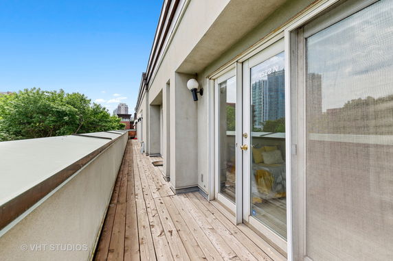Rooftop with wooden decking and glass doors leading to interior spaces.