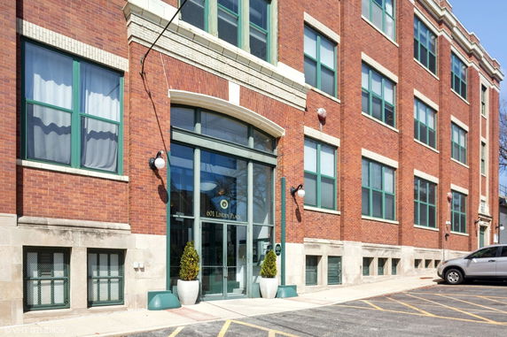 Front view of a three-story brick building with large glass entrance and windows.