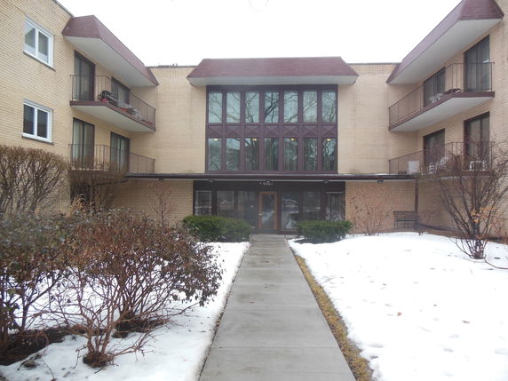Front view of a three-story apartment building with balconies and a central entrance.