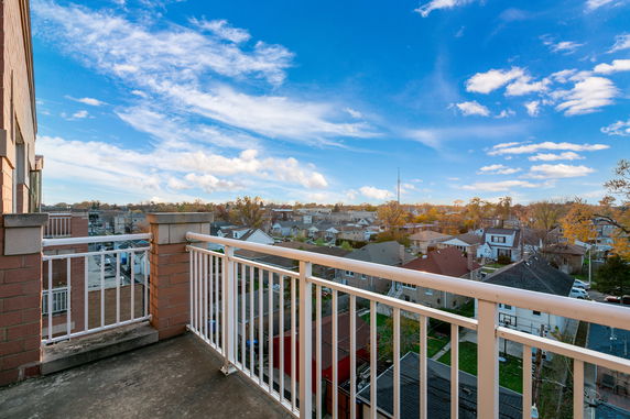 Panoramic view from a building balcony overlooking residential rooftops and distant scenery.