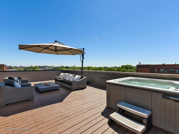 Rooftop with hot tub, seating area, and umbrella.