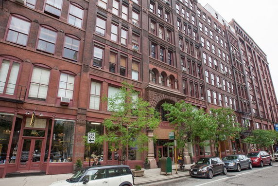 Front view of a large multi-story brick building with numerous windows and an entrance archway.