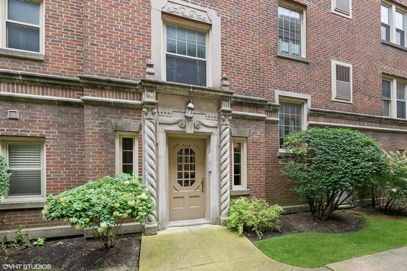 Front view of a brick multi-story building with decorative stonework around the entrance.