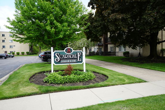 Front view of a condominium building with adjacent parking area.