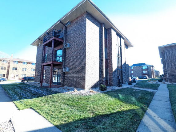 Front view of a multi-story brick apartment building with balconies.